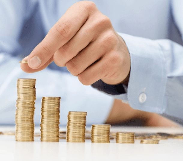 Hand adding coins to stacks of money.