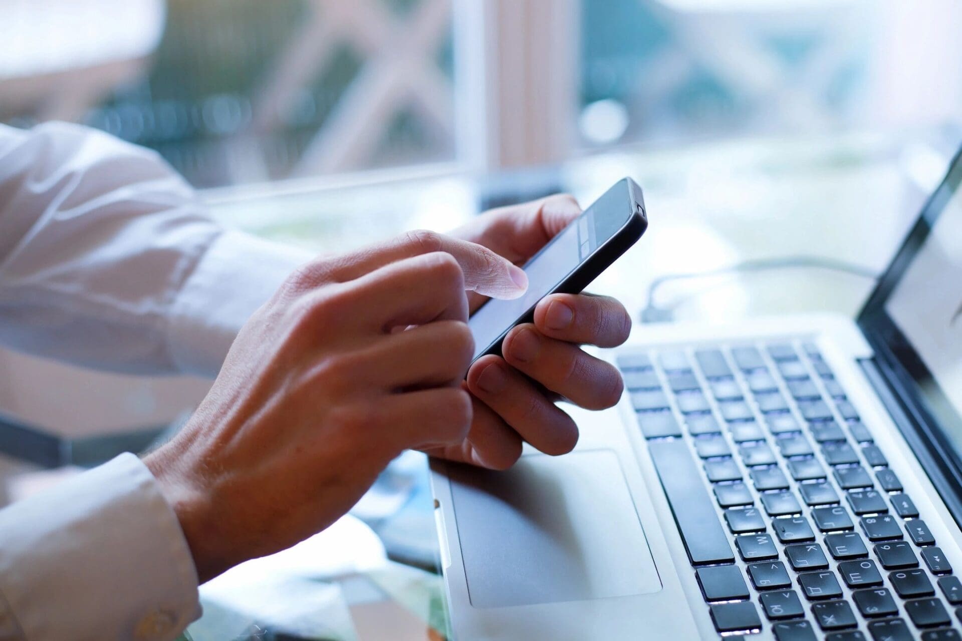 Person using phone near laptop.