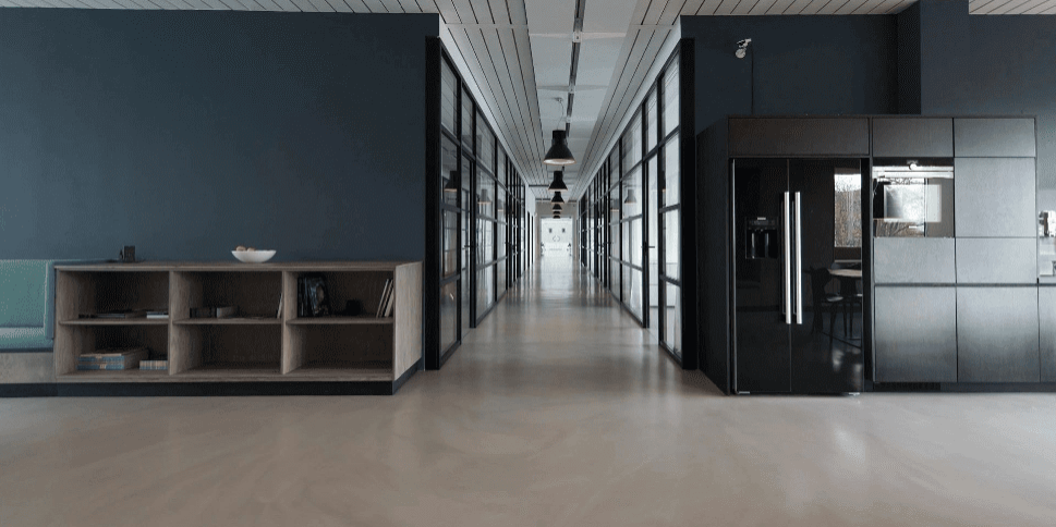 Modern office hallway with shelving and appliances.